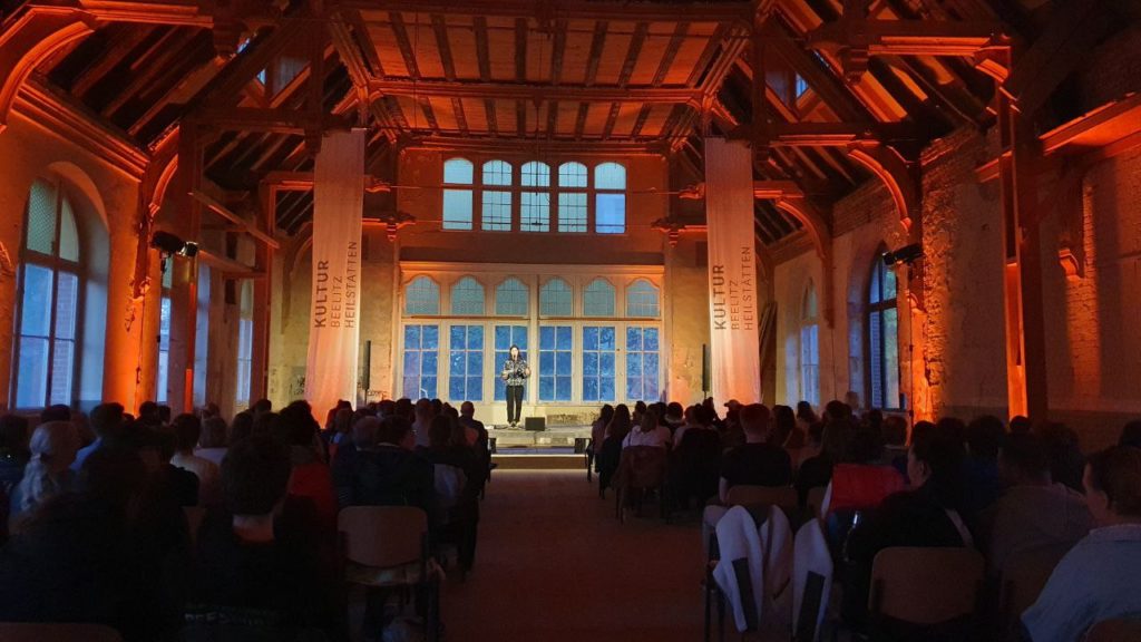 Auf dem Bild zu sehen ist eine Teilnehmerin am Poetry Slam in einem der historischen Räume in Beelitz-Heilstätten